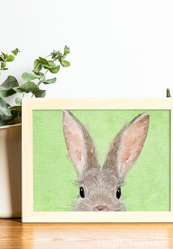 Easter printable of a bunny face drawn on a green watercolor background.