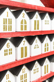 Close up angled shot of the paper houses on the DIY advent calendar with gold tissue paper covering the openings.