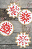 Four handmade Christmas ornaments with cross-stitched design on them.