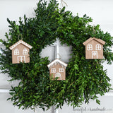 Square photo of gingerbread house paper Christmas ornaments hanging on a wreath.