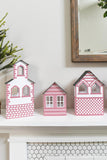 Three paper Christmas houses with red details, including a simple church.