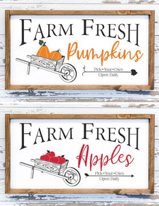 Farm fresh pumpkins and farm fresh apples signs with wheelbarrows full of produce.
