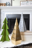 Gold, silver and green painted paper Christmas trees on a tray in front of the fireplace.