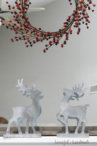 Christmas reindeer figurines made from paper and painted to look like metal on a Christmas mantel.