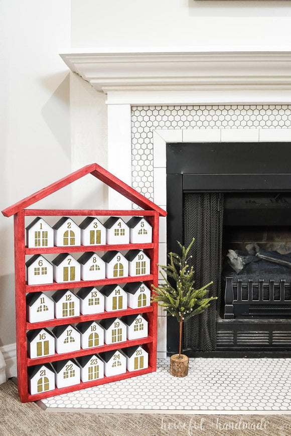 Red house shaped shelf with 25 paper houses as a DIY advent calendar.