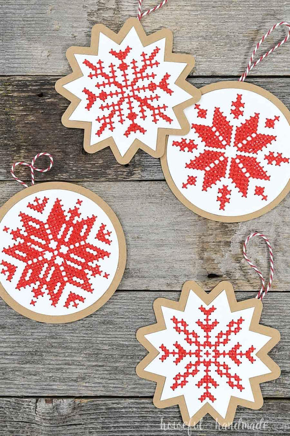 Four handmade Christmas ornaments with cross-stitched design on them.