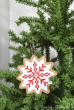 Snowflake design on a paper Christmas ornament hanging on a tree.