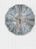 Rusted metal textured clock made out of paper hanging on a white wall.