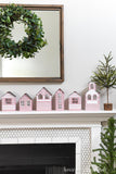 Five different designs on paper Christmas houses sitting on the mantle.